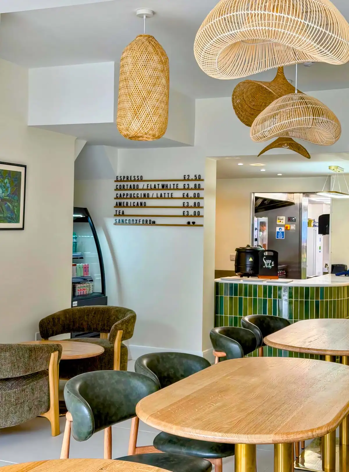 Inside SANCO Kitchen in Headington, with woven lamps and a green-tiled coffee counter